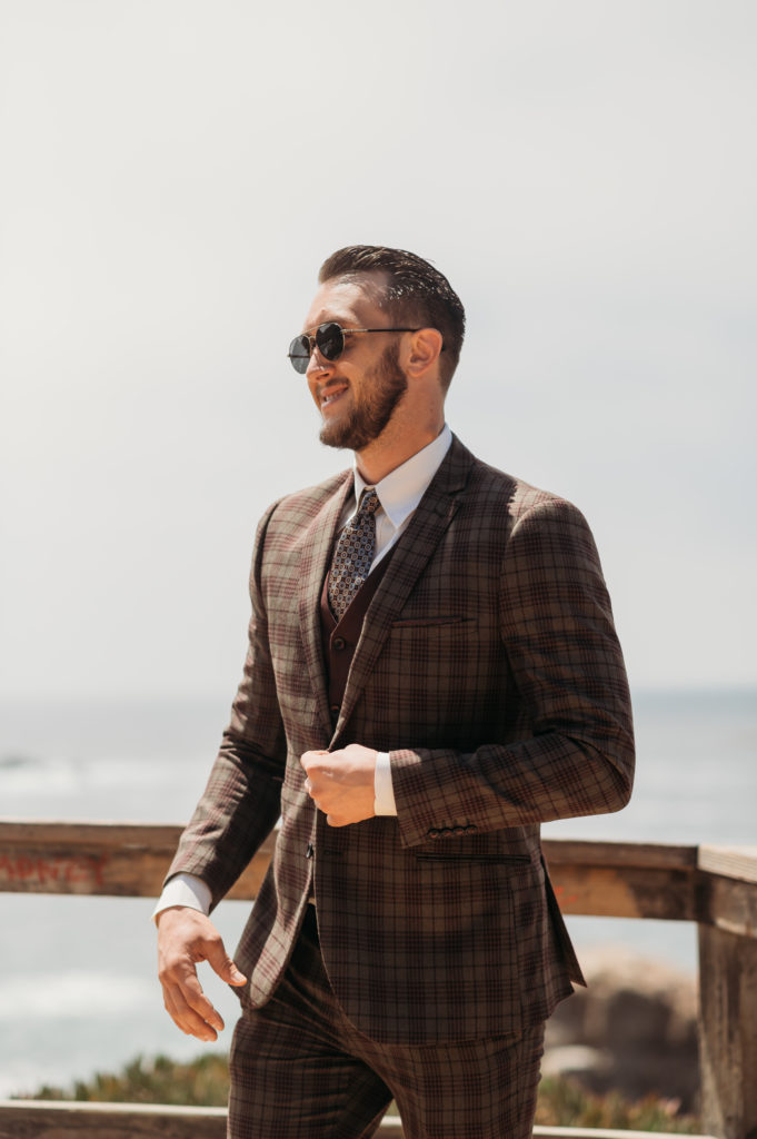 Groom during first look in Big Sur California on a sunny day with a suit and sunglasses