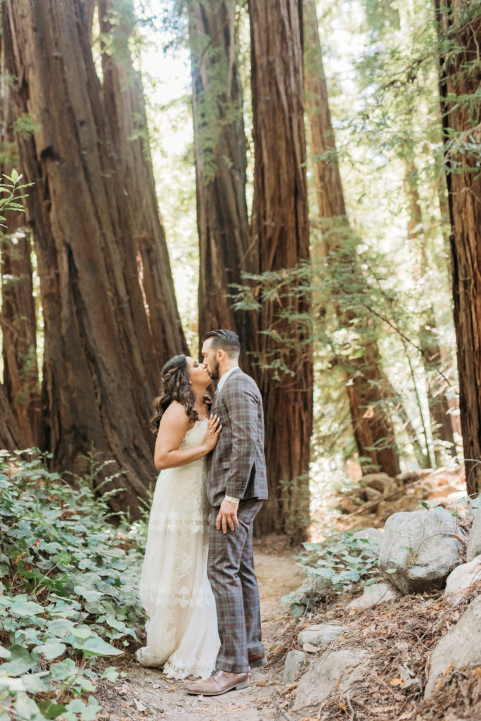 Forest kisses with bride and groom on path on a sunny day.